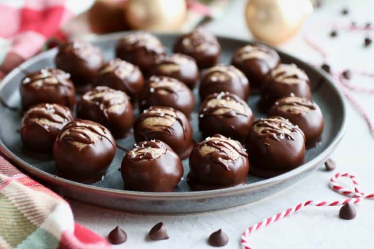 Several Buckeyes dipped in chocolate on a metal tray.