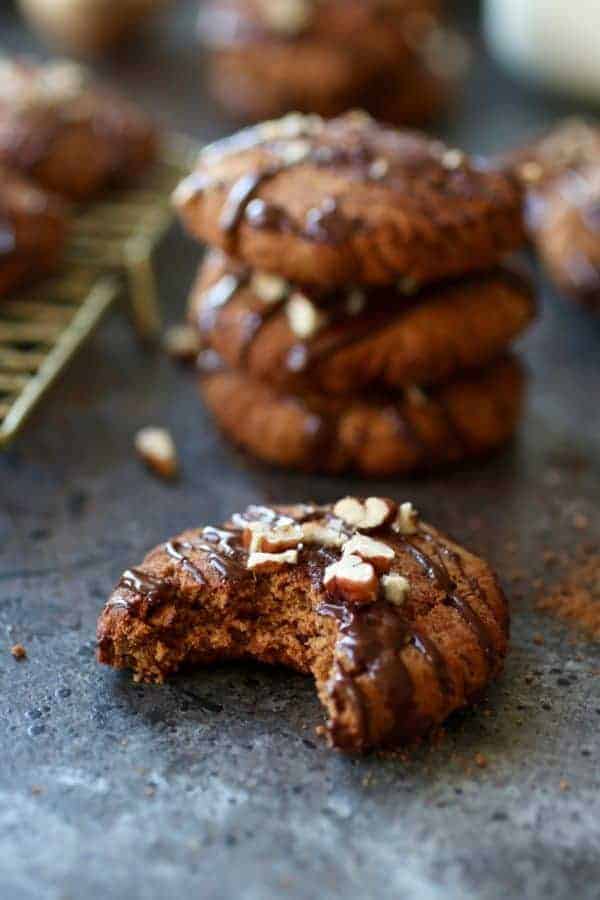 Close up side view of a Paleo Soft Batch Ginger Molasses Cookie missing a bite with a stack of three cookies in the background