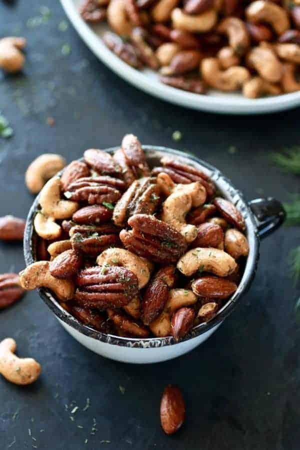 Ranch Roasted Mixed Nuts in a white antique tea cup. Photo taken on a dark background.