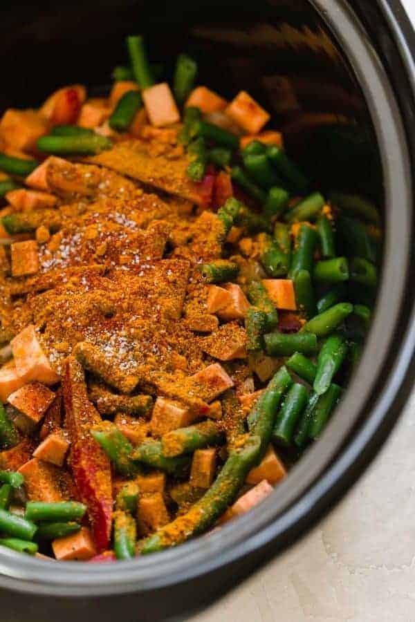 Overhead shot of the Slow Cooker Sweet Potato Chicken Curry ingredients in a black slow cooker. 