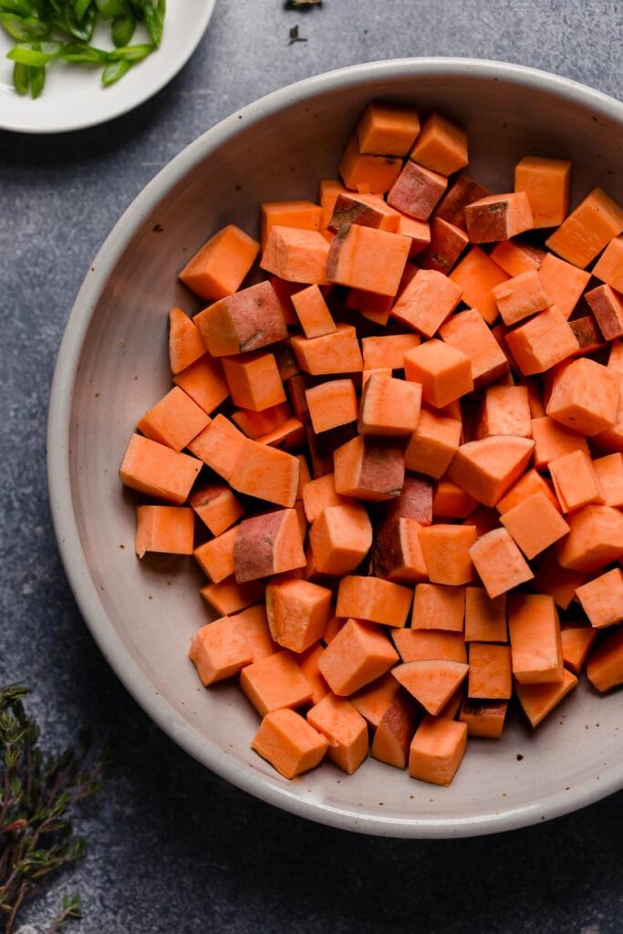 Overhead view of diced sweet potato in a light gray bowl. 