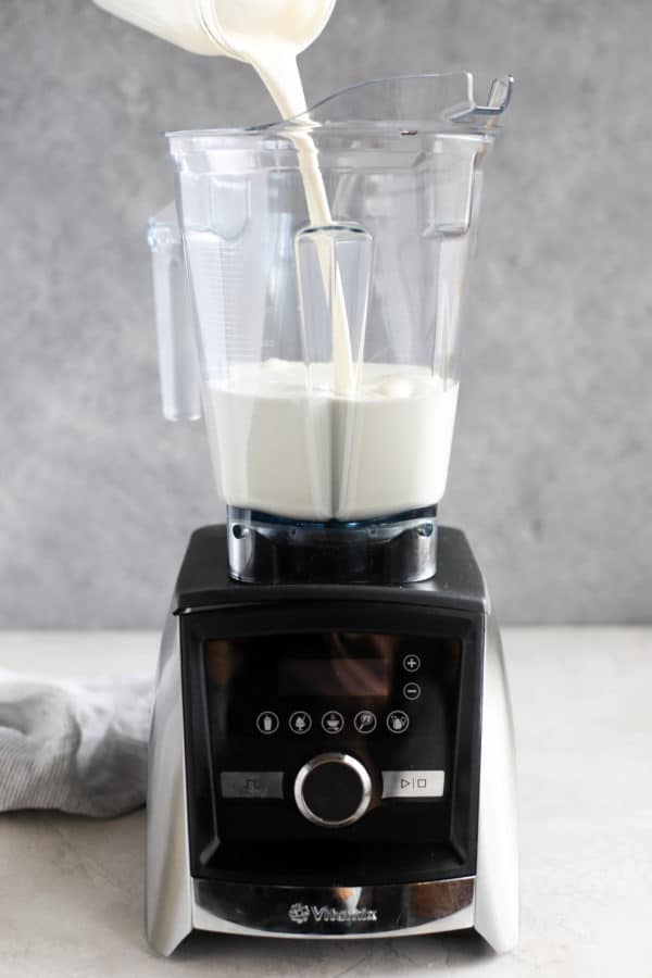 Pouring heavy cream from a jar into a Vitamix blender. 