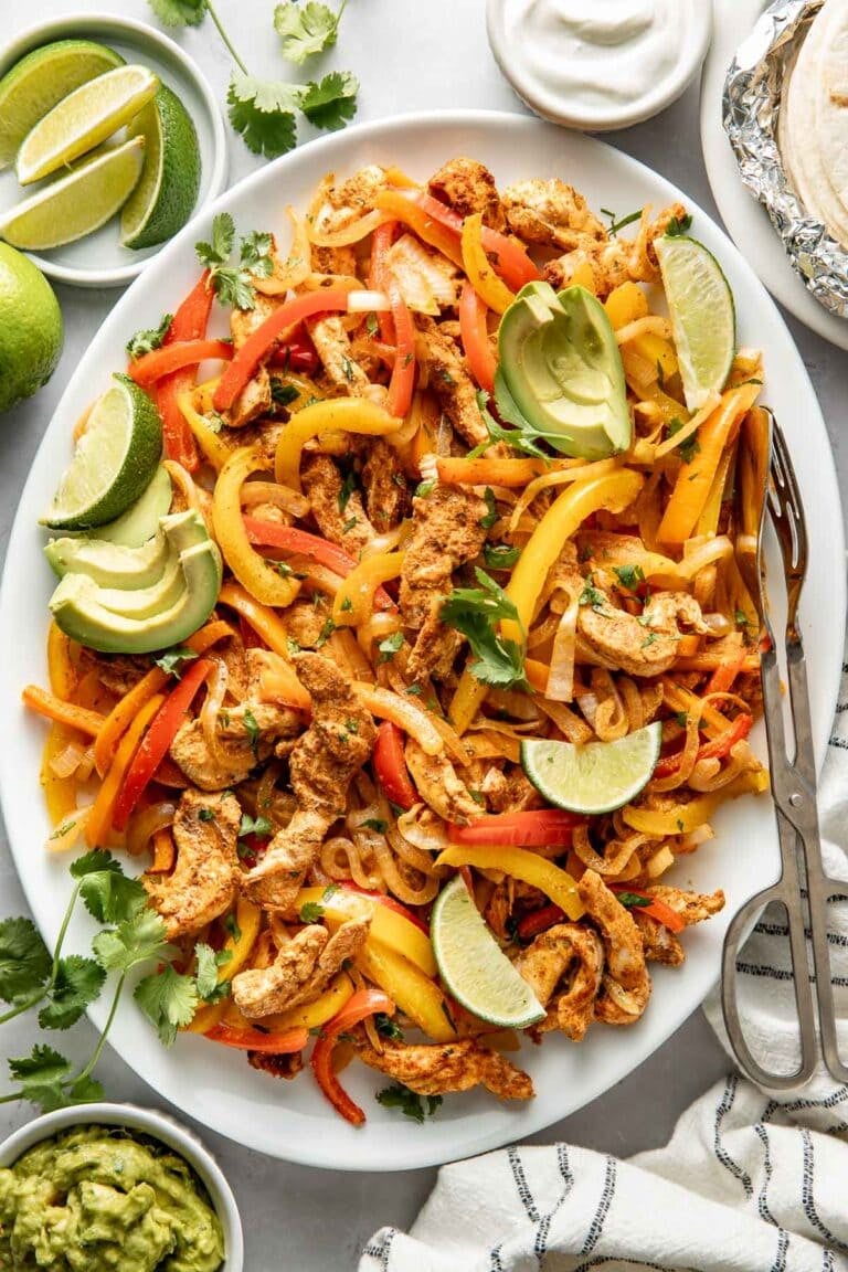Overhead view of a platter filled with chicken fajitas topped with fresh cilantro.