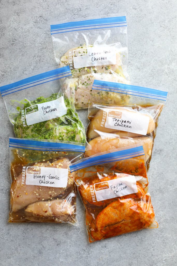 Five different chicken marinades in ziplock bags arranged together on counter.