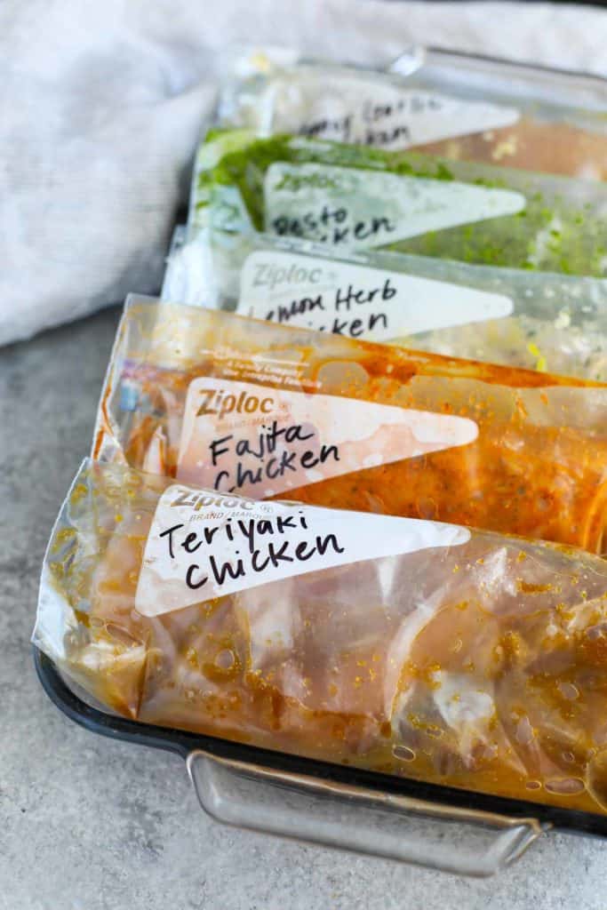 5 zip-top plastic bags marinated chicken contained in a rectangular glass dish