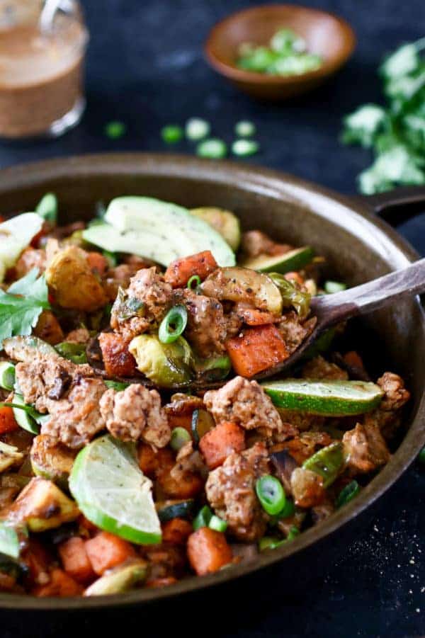 Photo of BBQ Ranch Turkey Veggie Skillet in a cast-iron topped with lime wedges, avocado, cilantro and green onion.