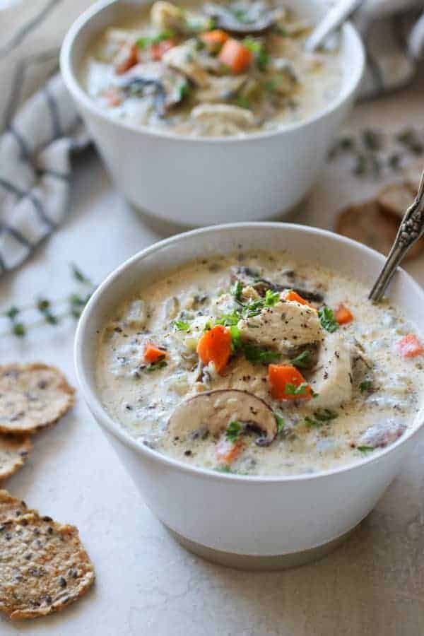 Photo of two white bowls of Slow Cooker Creamy Chicken Wild Rice Soup.