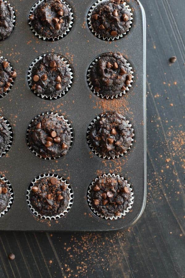 Pan of Paleo Double Chocolate Beet Brownies out of the oven on a black wooden table top dusted with cocoa powder. 