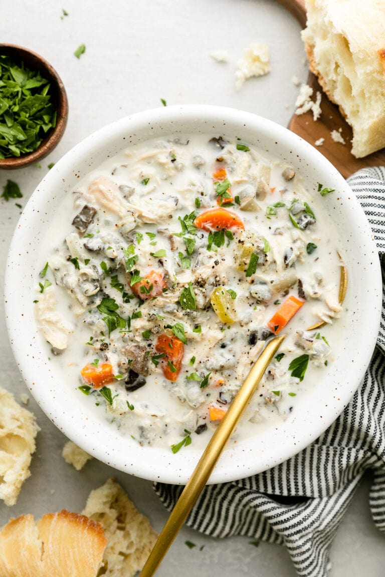 Overhead view white bowl filled with creamy slow cooker chicken and wild rice soup