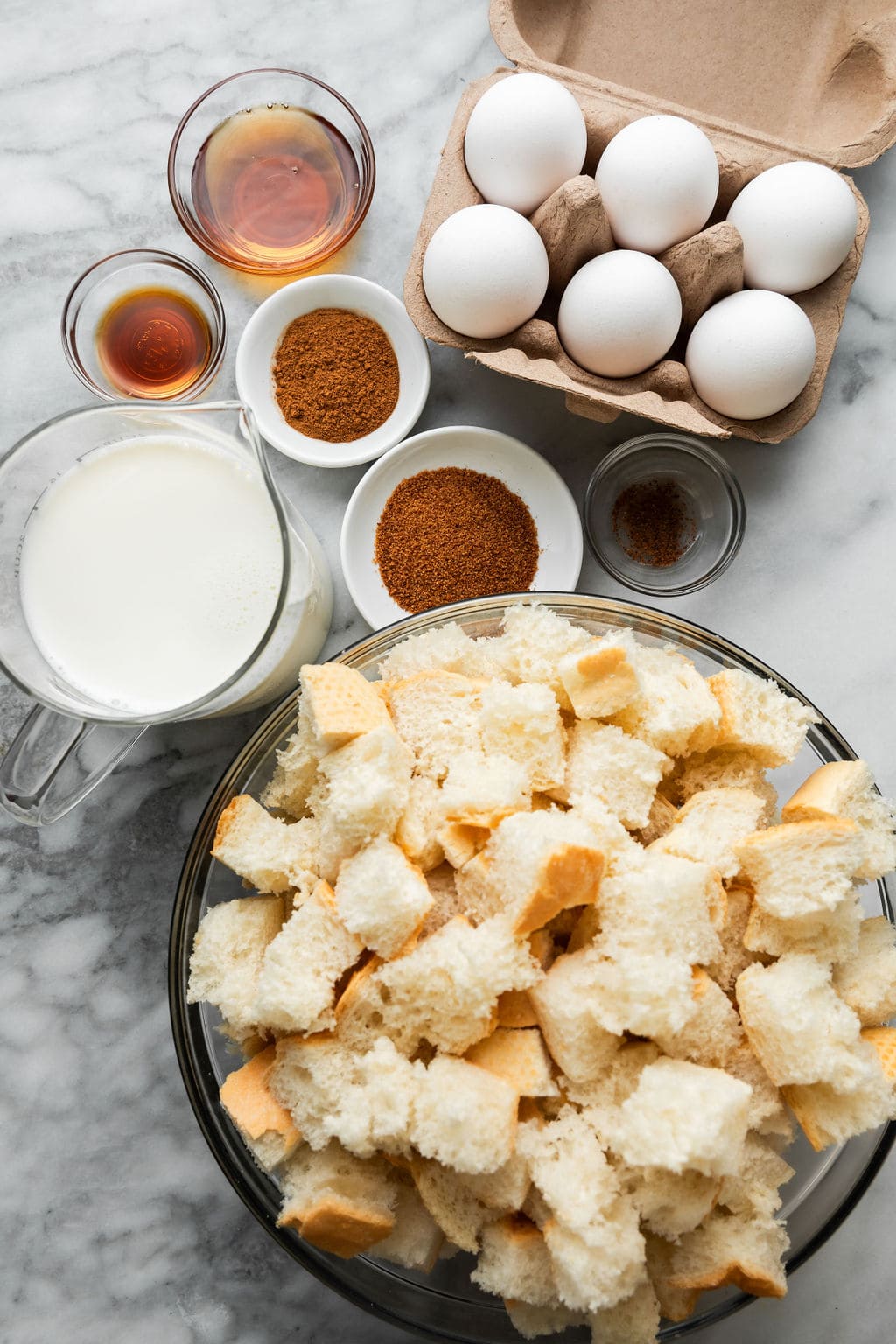 Overhead view all ingredients for crockpot french toast casserole arranged together in small bowls.
