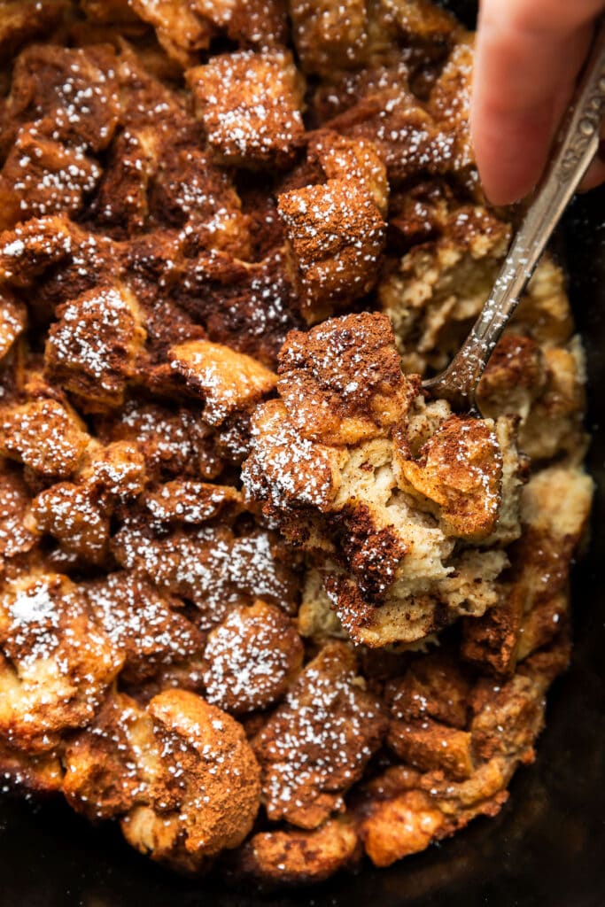 A silver spoon scooping up serving of French toast casserole from crockpot