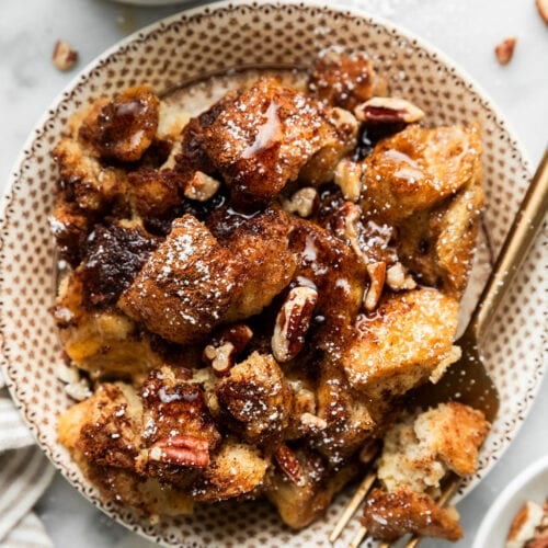 Overhead view serving of crockpot French toast casserole on plate topped with maple syrup and pecans