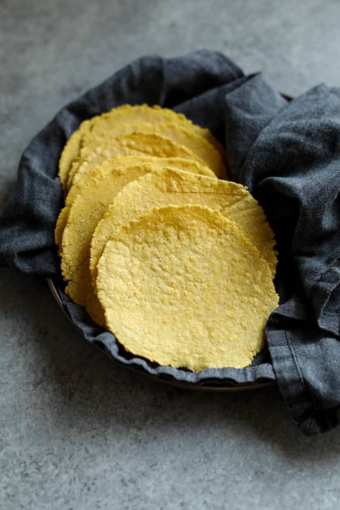 A napkin-lined basket filled with fresh corn tortillas