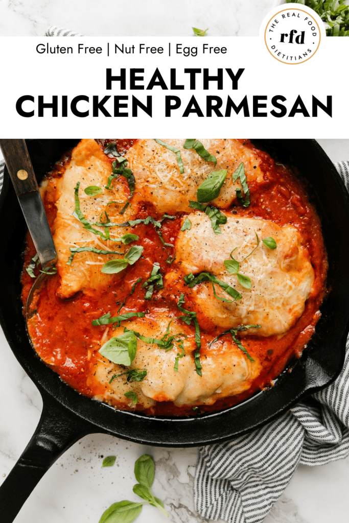Cast iron skillet with chicken parmesan in marinara sauce, fresh basil over top.