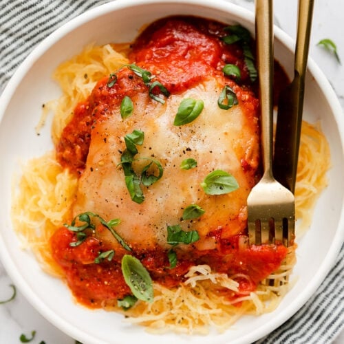 Overhead view chicken parmesan served over spaghetti squash strands in white bowl