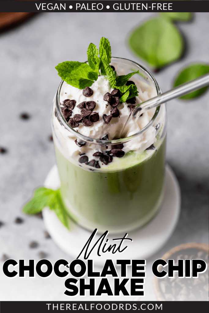 A Shamrock Shake made with spinach in a glass cup topped with whipped cream, fresh mint, and mini chocolate chips