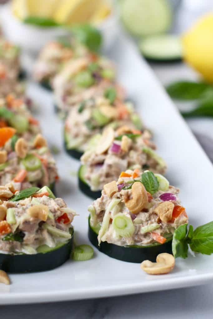 Plate of cucumber slices topped with tuna salad containing onions, cashews, broccoli slaw and peppers