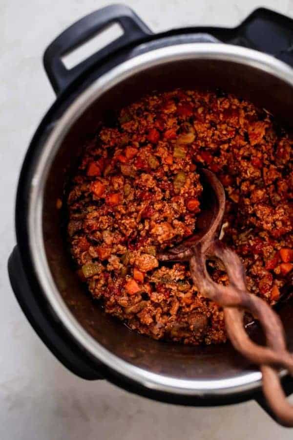 Overhead view instant pot filled with turkey mushroom bolognese with wooden spoon in bolognese