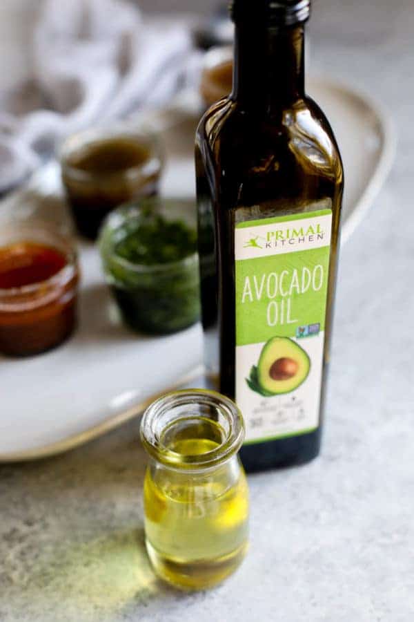 Glass jar of Primal Kitchen Avocado oil with small glass jar filled with avocado oil