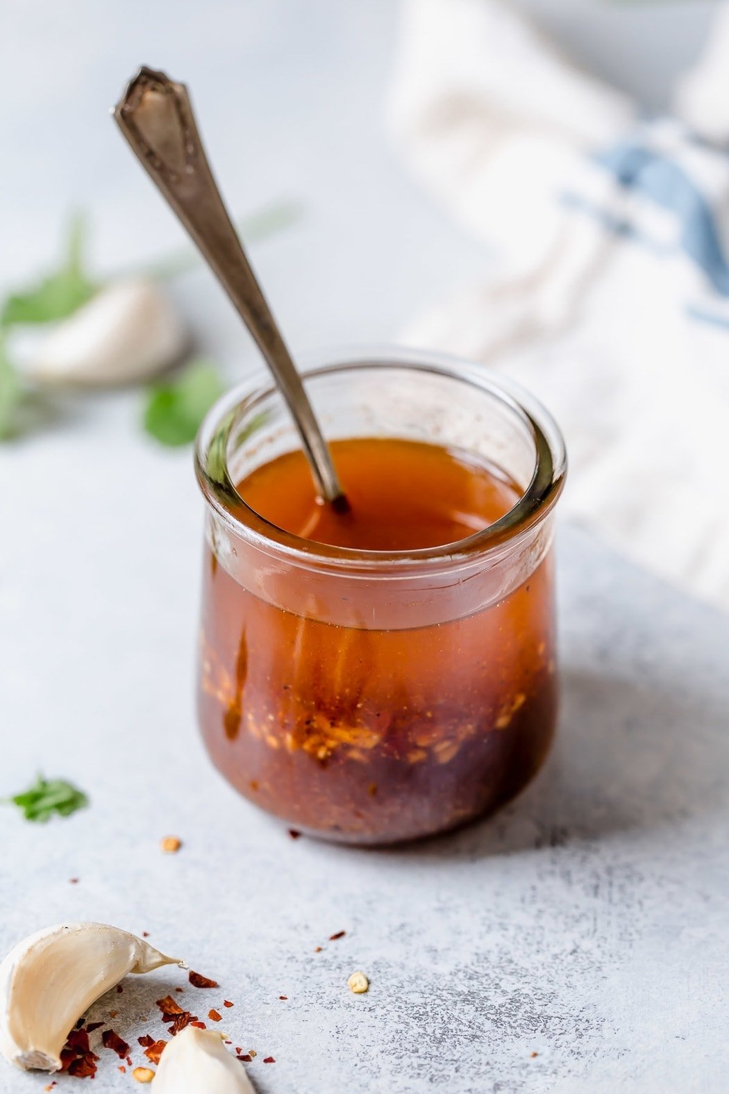 Chili Lime Vinaigrette mixed together in a small jar with a spoon in the vinaigrette stirring together. For a black bean and corn salsa with avocado.