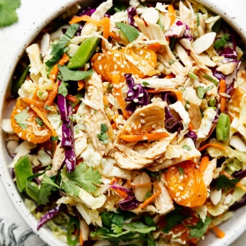 Overhead view bowl filled with Chinese-inspired Chicken Salad topped with mandarin oranges and sesame seeds.