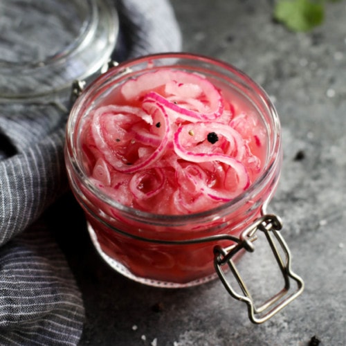 Overhead view of quick pickled red onions in a small glass jar.