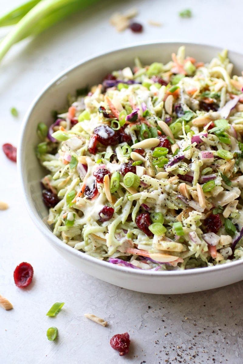 Close up view creamy ranch coated broccoli slaw with dried cranberries in a stone bowl