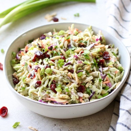 Overhead view white bowl filled with creamy ranch broccoli slaw with dried cranberries.