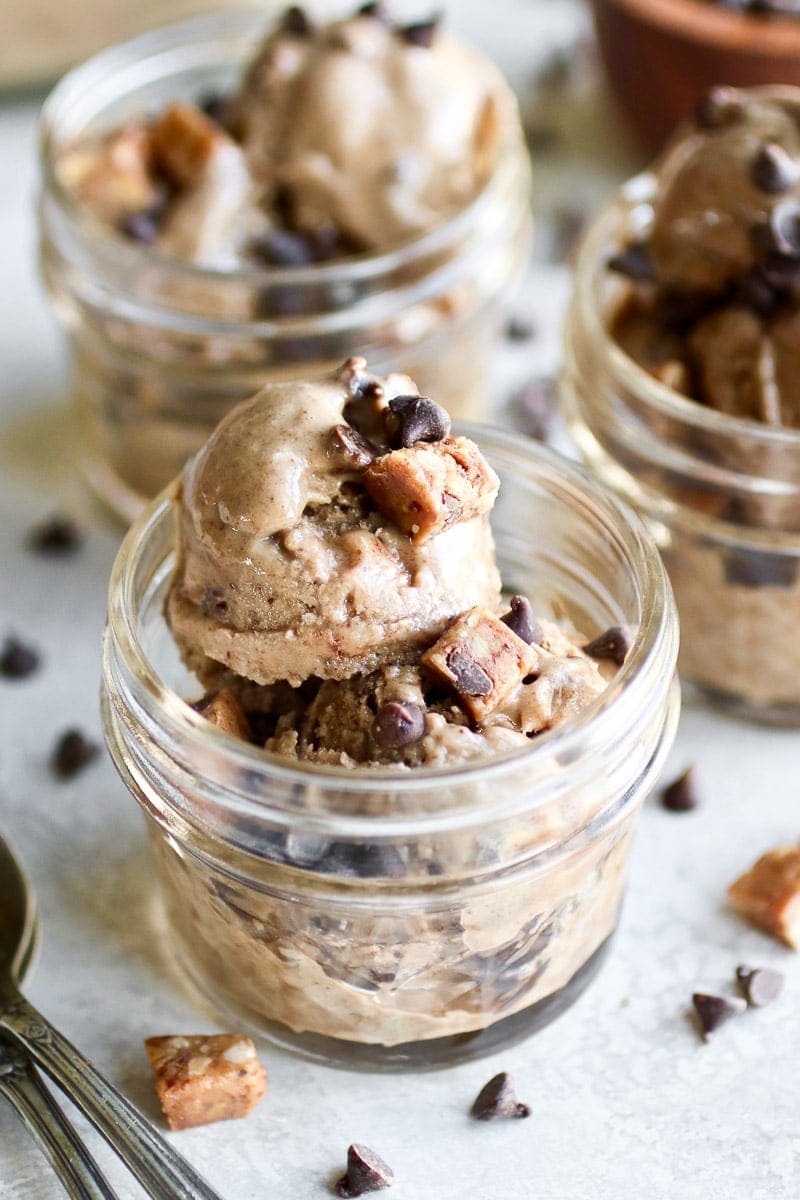 Photo of Almond Butter Banana Nice Cream in a small mason jar topped with chocolate chips and pieces of Caveman Collagen Bar.