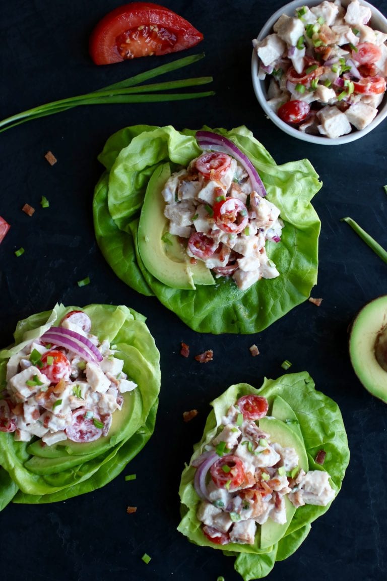 Three BLT chicken salad lettuce wraps with sliced red onion on tops. 