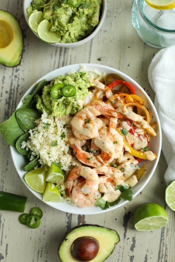 Overhead photo of One-Pan Shrimp Fajita Bowls with limes and avocado halves next to it. Photo is linked to the recipe. 