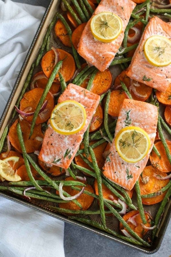 Overhead photo of One-Pan Salmon and Veggie Bake (salmon filets over a bed of sliced sweet potatoes, red onion and green beans. Photo is linked to the recipe. 