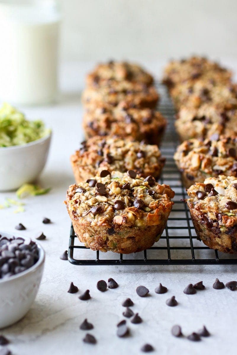 A cooling rack filled with zucchini banana baked oatmeal cups topped with chocolate chips. 