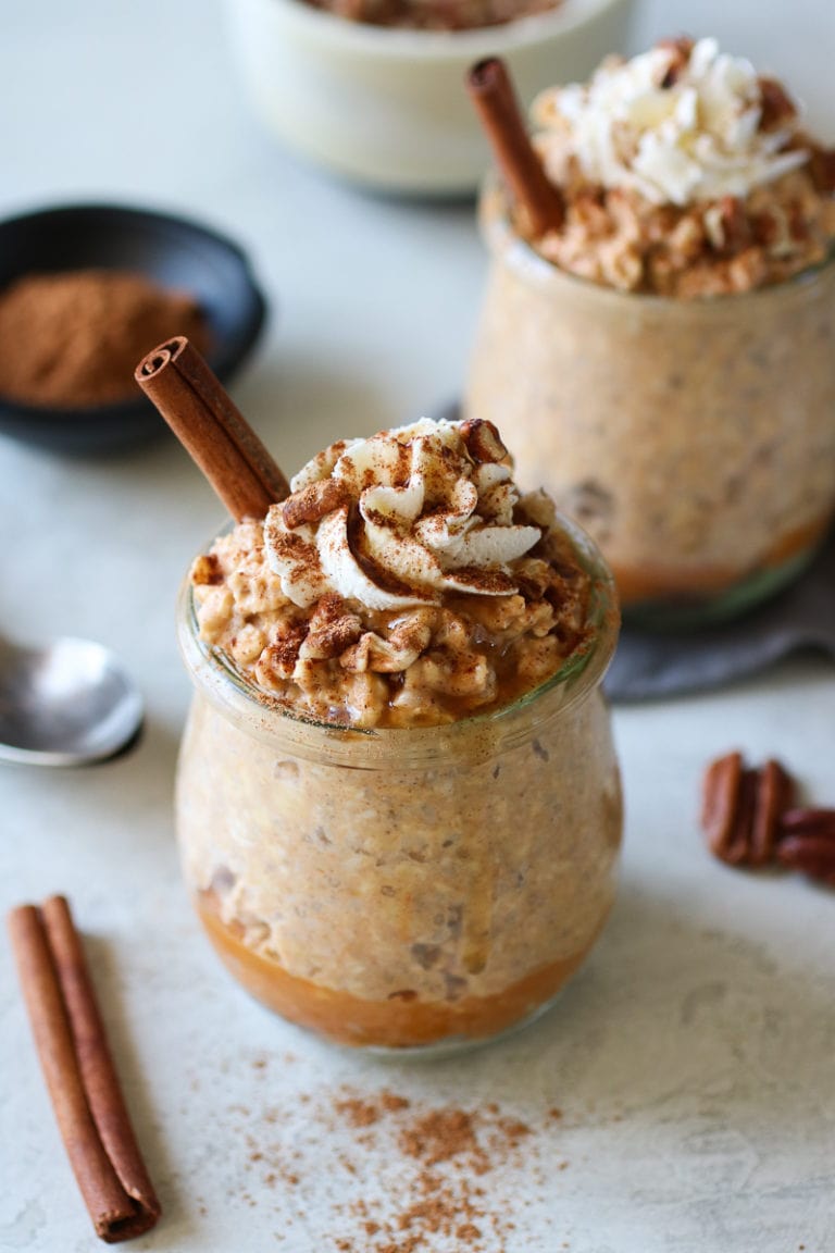 Pumpkin Pie Overnight Oats in small glass containers topped with whipped cream and cinnamon. 