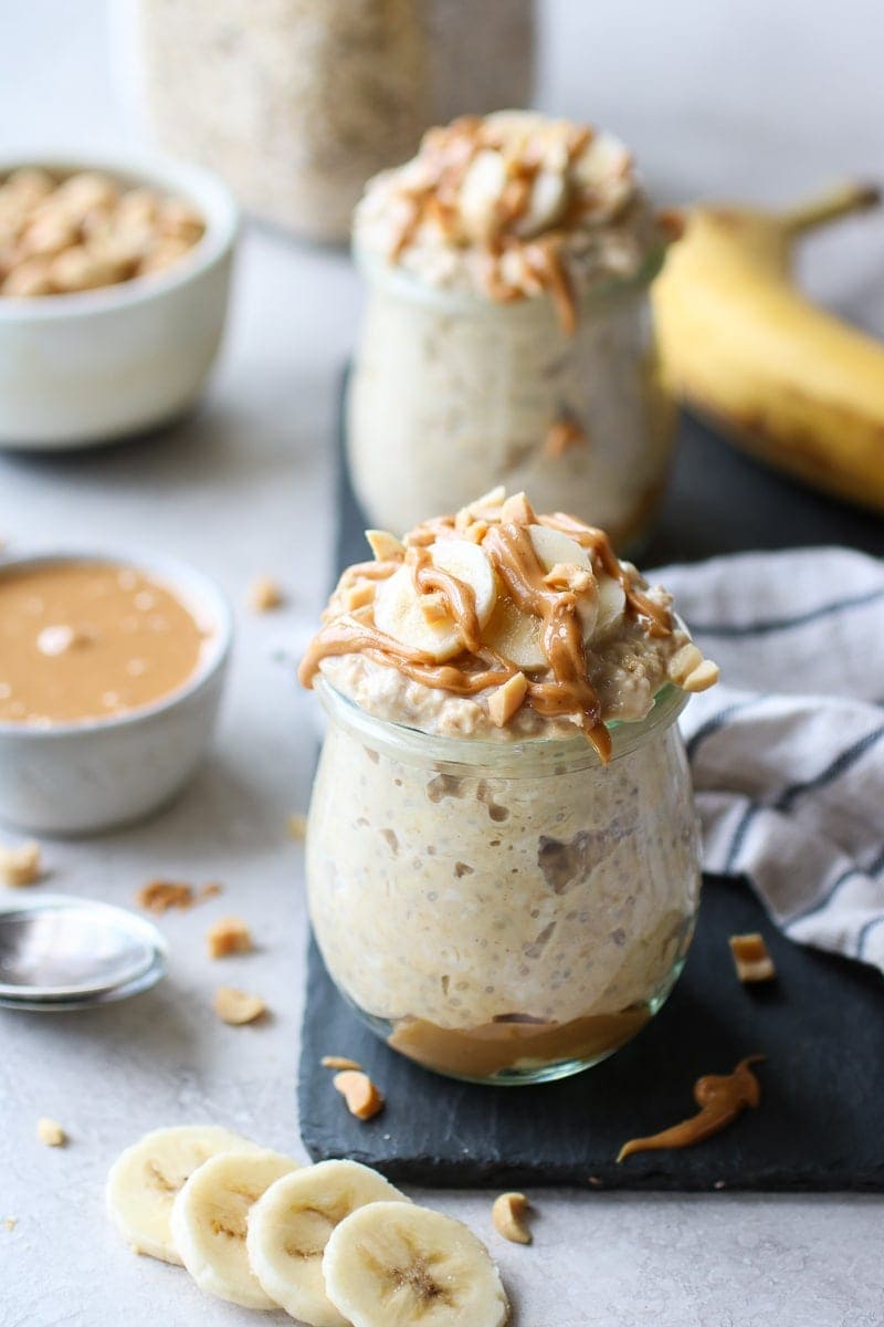 Peanut Butter Banana Overnight Oats in small glass jars topped with banana slices and peanut butter drizzle