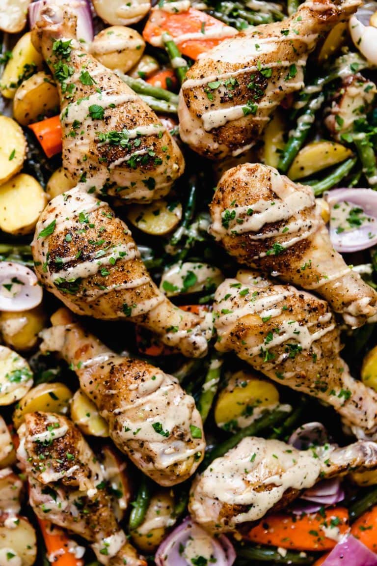 Overhead view of a One-Pan Chicken Caesar Veggie Bake drizzled with a Caesar dressing.