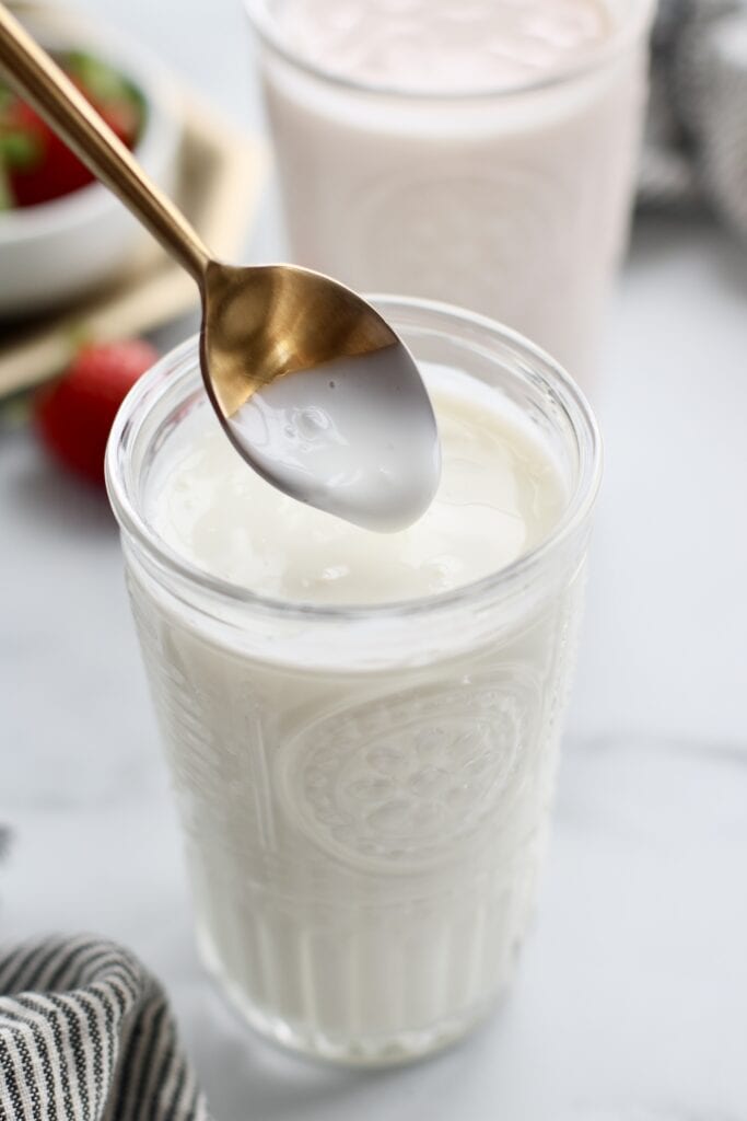 Close up view of a spoon dipped in kefir. 