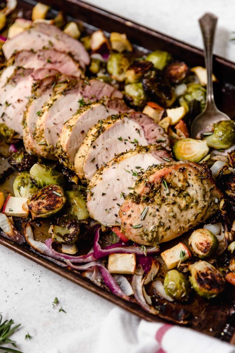 A freshly baked pan of roasted pork loin with apples on a sheet pan. 