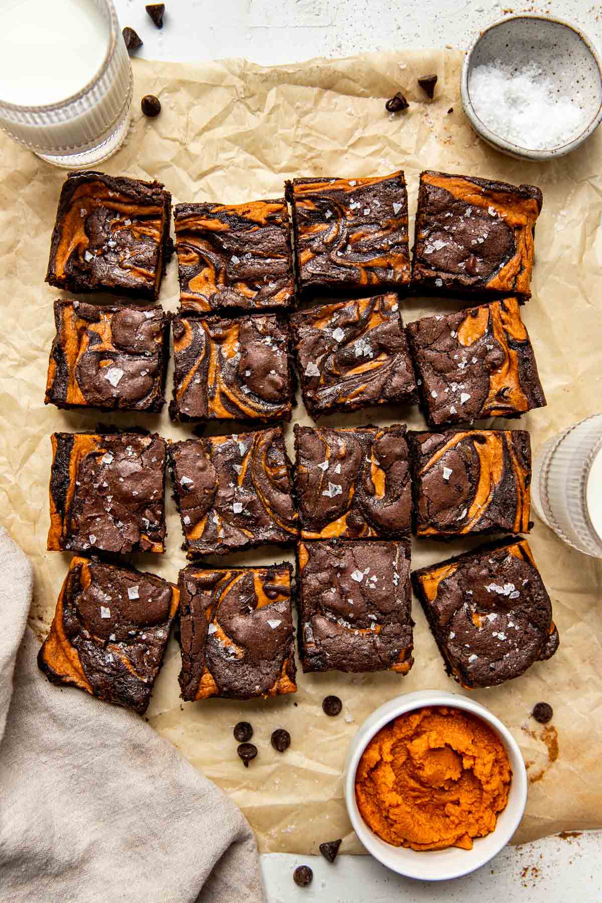 Overhead view of a freshly baked batch of Pumpkin Brownies cut into squares and topped with flakey sea salt. 