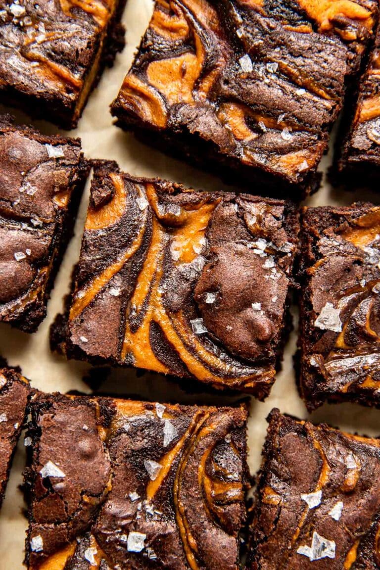 Close up overhead view of pumpkin brownies cut into squares on parchment paper.  