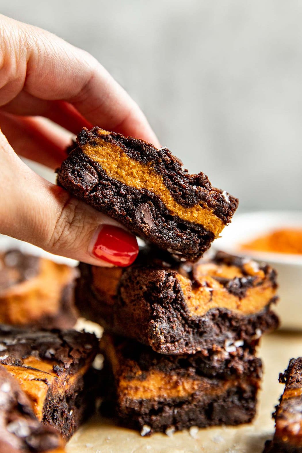 A hand grabbing a freshly baked piece of Pumpkin Brownie. 