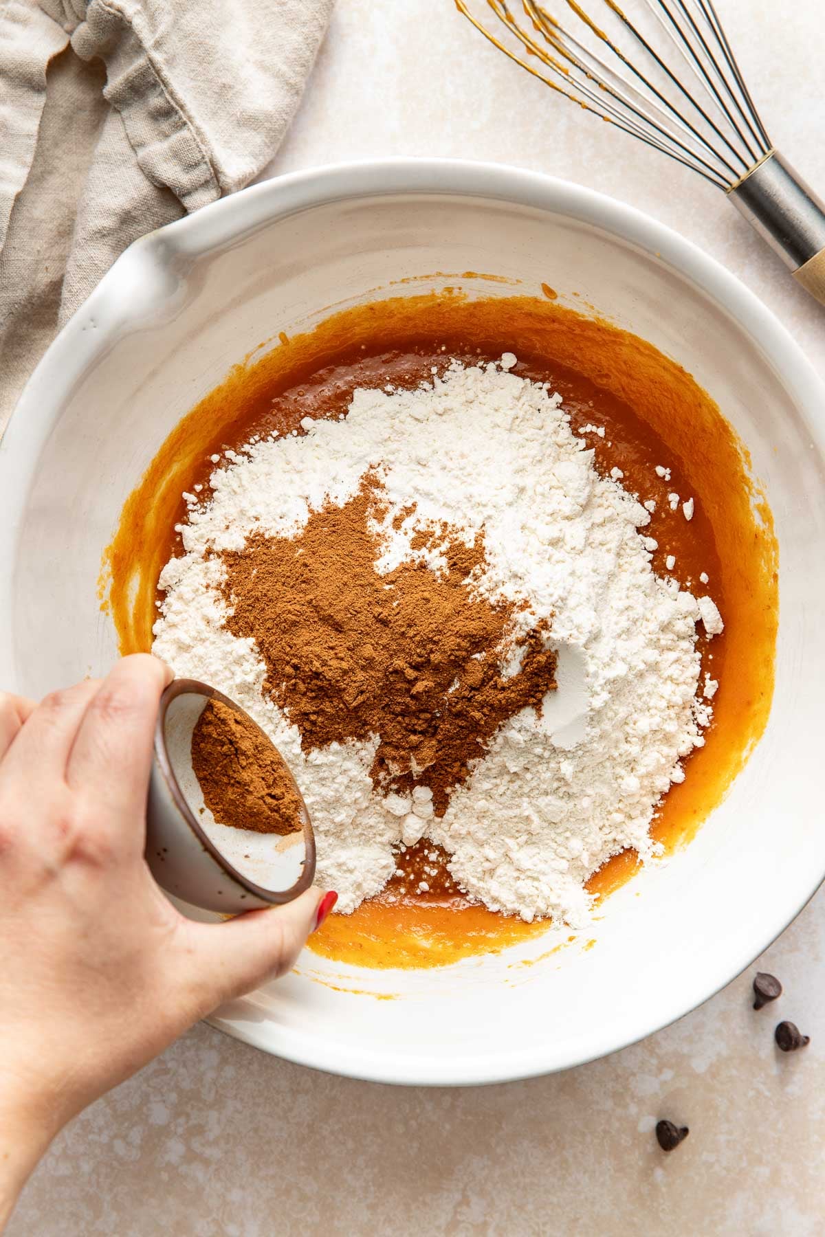 Dry ingredients being added to wet ingredients for pumpkin chocolate chip bars in a bowl.