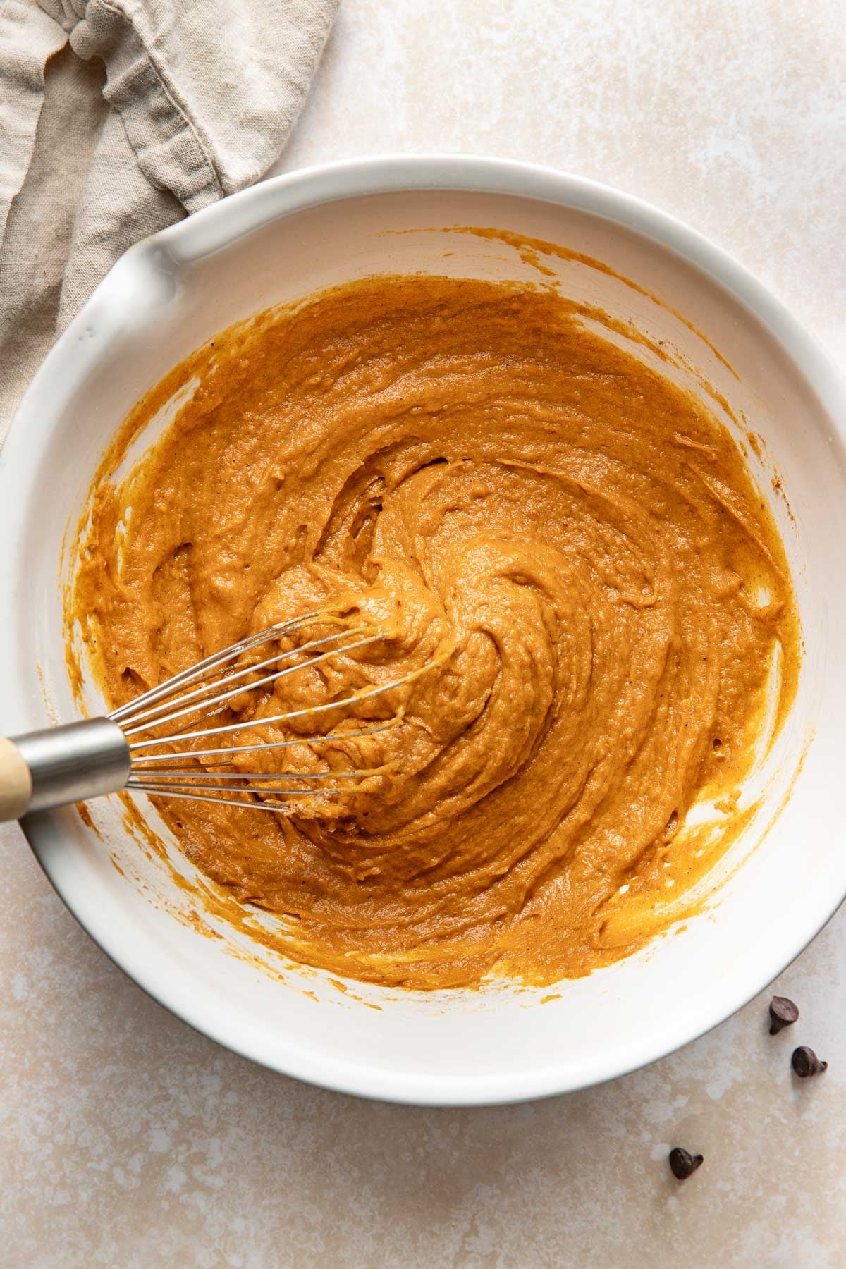 Batter for pumpkin chocolate chip bars in a bowl, a whisk sticking out.