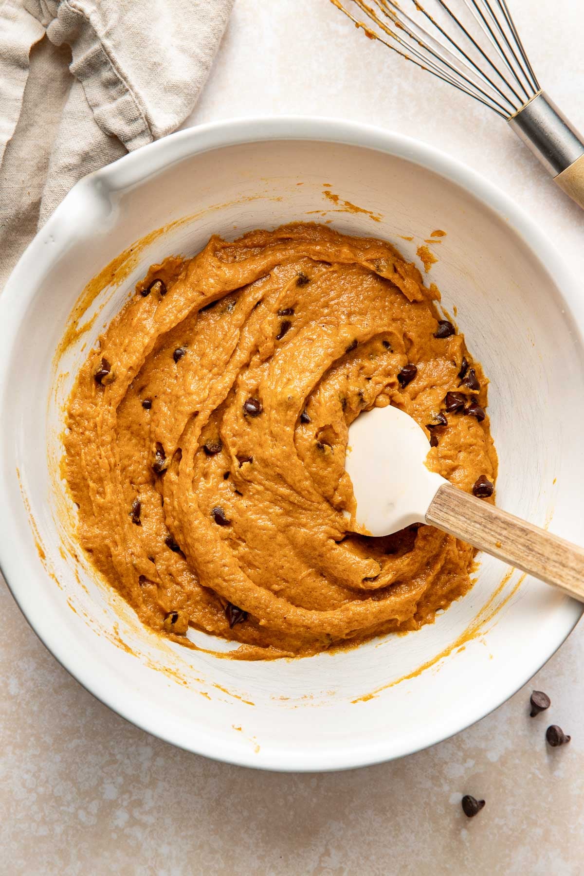 Pumpkin chocolate chip bar batter in a bowl, a rubber spatula sticking out.