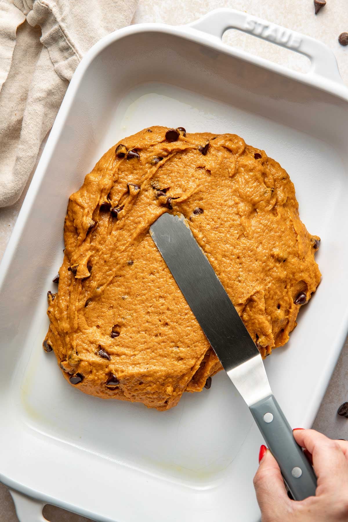 Pumpkin chocolate chip bar batter being spread out in a baking dish.