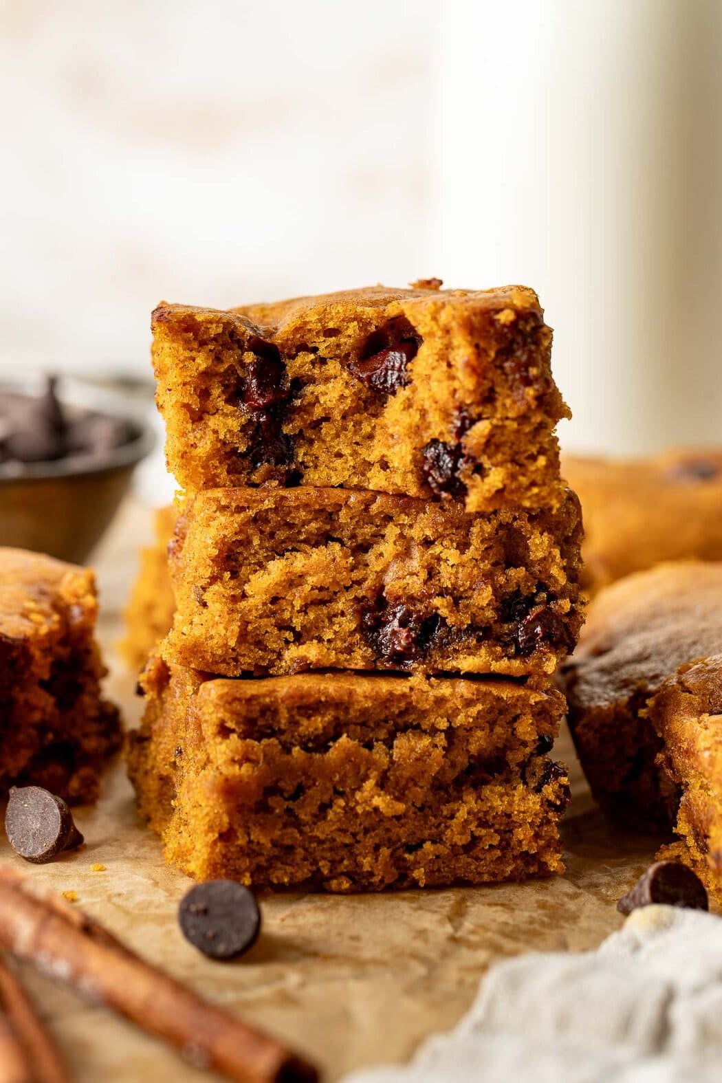 A stack of three pumpkin chocolate chip bars, the top bar missing a bite.