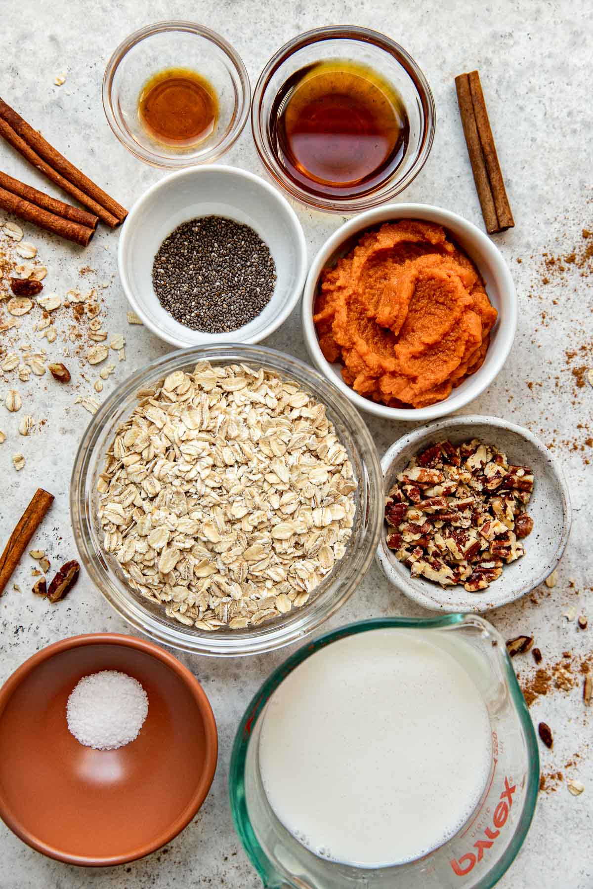 Overhead view of a variety of ingredients for Pumpkin Overnight Oats in different bowls. 