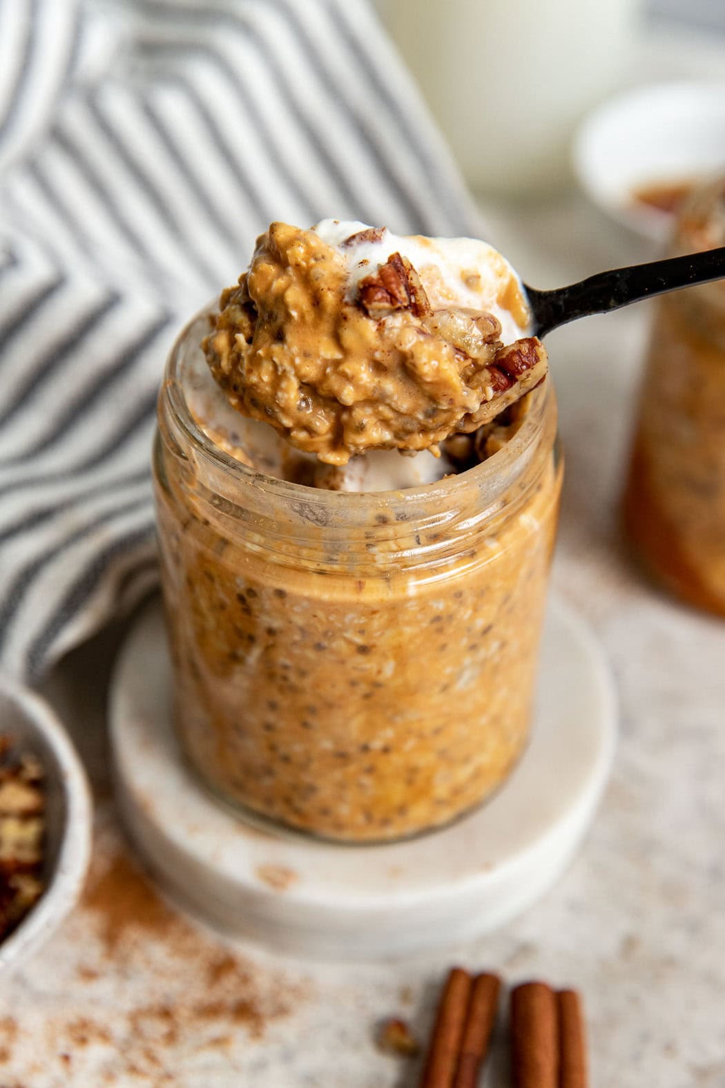 Close up view of a spoon scooping a bite of Pumpkin Overnight Oats out of a glass jar. 