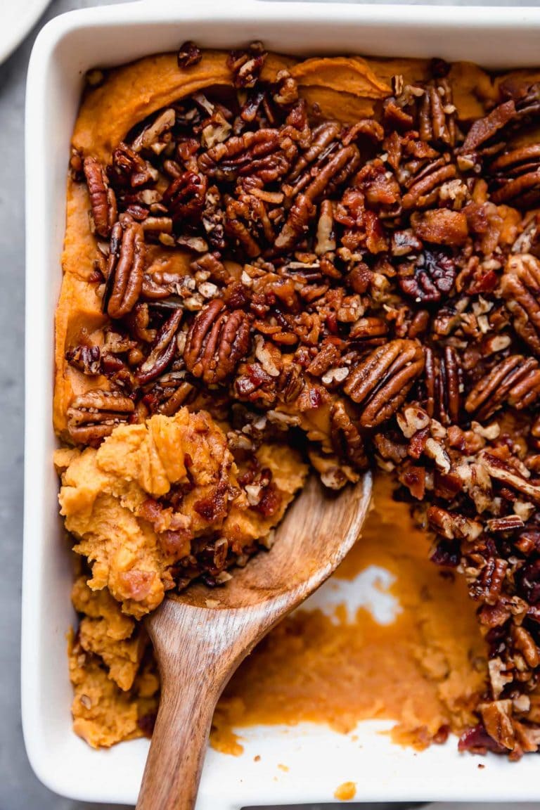 Sweet potato casserole in a white baking dish topped with chopped pecans.