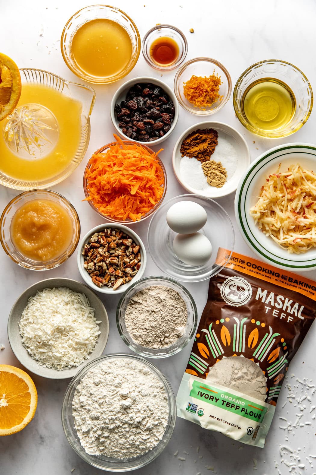 Overhead view of a variety of ingredients for Morning Glory Muffins in different sized bowls. 